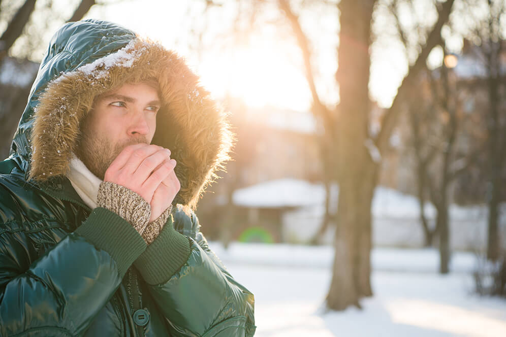 Ein Mann schützt sich vor Unterkühlung, indem er eine dicke Jacke trägt, um mögliche Entzündungen in der Blase zu verhindern. Praktische Vorsichtsmaßnahmen zur Förderung der Gesundheit in kalten Umgebungen.